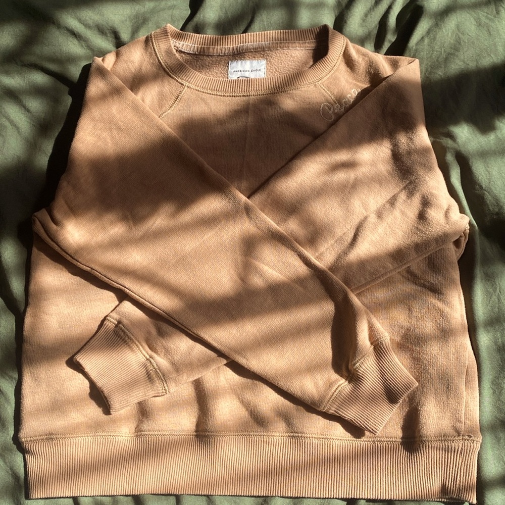 yellowish sweatshirt with “peace” embroidered on the shoulder